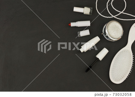 Cosmetics in white packaging on a dark background, lipstick, mascara, nail polish. Banner with space for text. 73032058