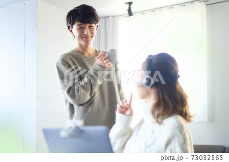 部屋で会話をする若い男女 部屋で会話をする若い男女 73032565