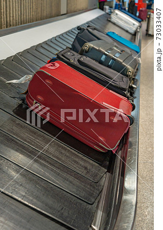 Suitcases on luggage conveyor belt at arrival department in airport Suitcases on luggage conveyor belt at arrival department in airport 73033407