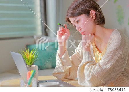 テレワーク_ペンを持ち首をかしげて考える女性 テレワーク_ペンを持ち首をかしげて考える女性 73033615