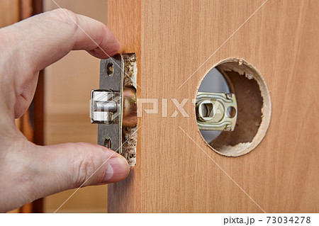 Carpenter shoves latch assembly of door knob through the edge bore. 73034278
