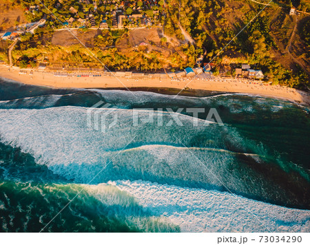 Aerial view of coastline at warm sunset and Bali beach. Perfect ocean waves for surfing Aerial view of coastline at warm sunset and Bali beach. Perfect ocean waves for surfing 73034290