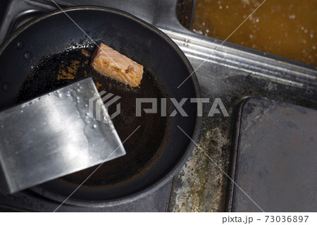 A piece of red fish in a black frying pan. 73036897
