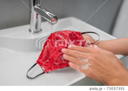 Washing cloth mask by hand after one use. Corona virus preventive face covering cleaning at home in sink Washing cloth mask by hand after one use. Corona virus preventive face covering cleaning at home in sink 73037391