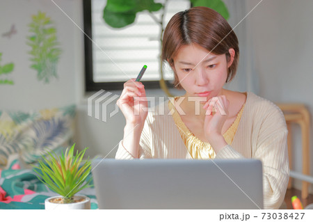 テレワーク_ペンを持ち考え込む女性_正面 73038427