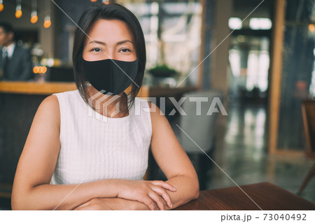 Asian mature business woman wearing protective face mask for coronavirus prevention in indoors public space as work office, restaurant, cafe 73040492