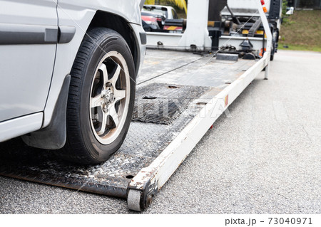 Cable attached to broken down car being pulled onto tow truck 73040971