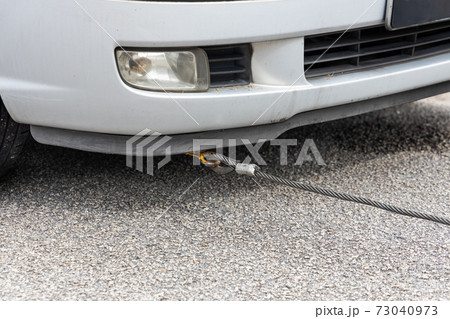 Cable attached to broken down car being pulled onto tow truck 73040973