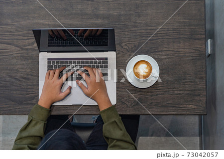 Aerial view of freelancer in hoodie working on laptop 73042057