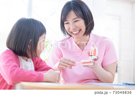歯医者　歯磨き指導を受ける女の子と医師 73049836