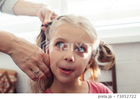Mom is combing her daughter's hair. Taking care of baby's hair. The concept of a happy childhood and a good attitude towards children. Happy family Mom is combing her daughter's hair. Taking care of baby's hair. The concept of a happy childhood and a good attitude towards children. Happy family 73052722