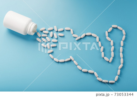Biceps from white dragees with vitamins and minerals, Protein from a jar on a blue background. Biceps from white dragees with vitamins and minerals, Protein from a jar on a blue background. 73053344