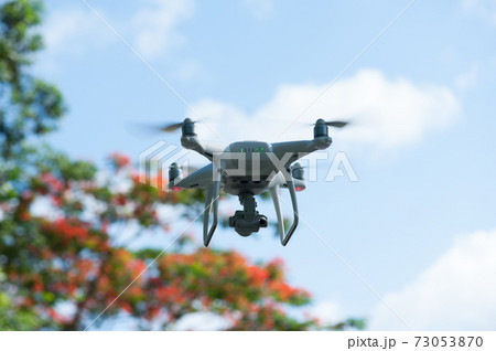 White drone with camera flying in summer White drone with camera flying in summer 73053870