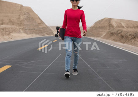 Asian woman skateboarder skateboarding in the wide world 73054395