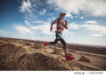 Woman trail runner cross country running  on sand desert dunes 73054397
