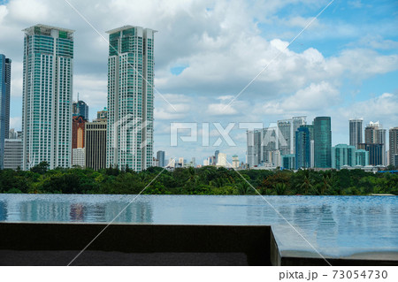 View of the city of Manila from the pool in a chic five-star hotel. Sunny weather. Skyscrapers in the background. An empty pool without tourists due to the COVID-19 coronavirus pandemic. 73054730