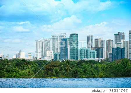 View of the city of Manila from the pool in a chic five-star hotel. Sunny weather. Skyscrapers in the background. An empty pool without tourists due to the COVID-19 coronavirus pandemic. 73054747