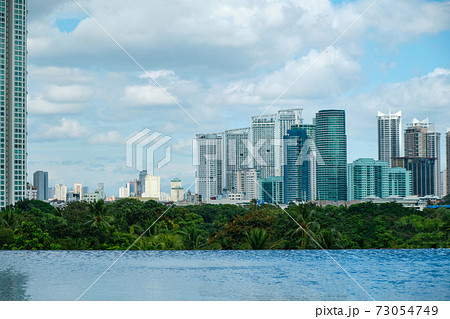 View of the city of Manila from the pool in a chic five-star hotel. Sunny weather. Skyscrapers in the background. An empty pool without tourists due to the COVID-19 coronavirus pandemic. 73054749