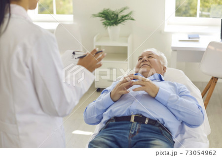 Senior patient listening to doctor lying on bed in hospital office during medical check-up Senior patient listening to doctor lying on bed in hospital office during medical check-up 73054962