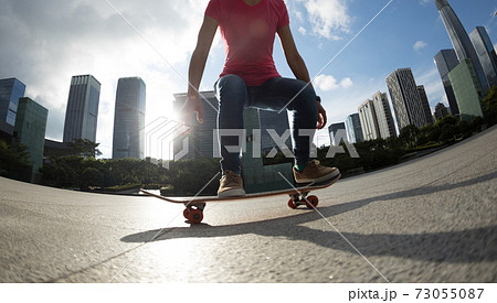 Asian woman skateboarder with skateboard in modern city 73055087