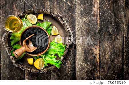 Black caviar with a glass of wine and greens. 73056319