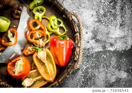 chopped sweet pepper in a wooden tray with a knife. chopped sweet pepper in a wooden tray with a knife. 73056545