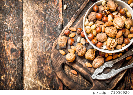 Nuts with Nutcracker in a bowl on the old Board. 73056920