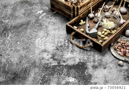 Fresh garlic with a press tool on a wooden tray. Fresh garlic with a press tool on a wooden tray. 73056921