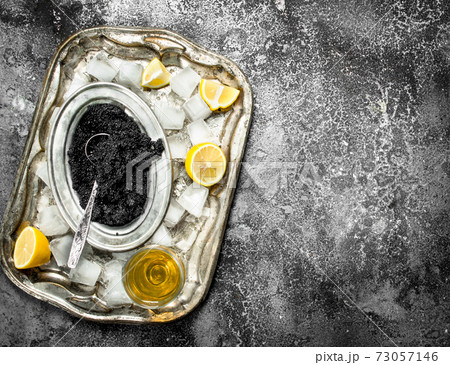 Black caviar with white wine and slices of lemon. 73057146