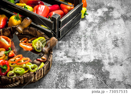 chopped sweet pepper in a wooden tray with a knife. 73057535
