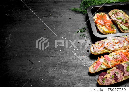 Sandwiches with bacon, salami, crab meat and vegetables. 73057770