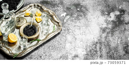 Vodka with black caviar and lemon. Vodka with black caviar and lemon. 73059371