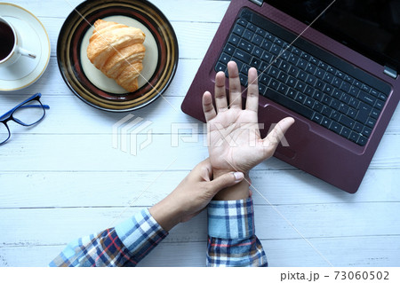 man suffering pain in hand while working on laptop man suffering pain in hand while working on laptop 73060502
