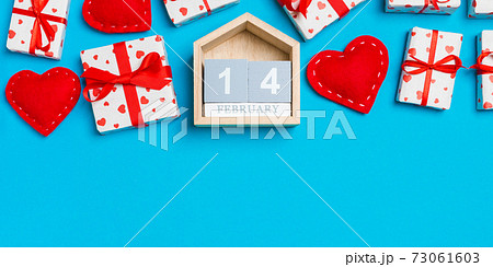 Top view of gift boxes, wooden calendar and red textile hearts on colorful background. The fourteenth of february. St Valentine's day concept with copy space Top view of gift boxes, wooden calendar and red textile hearts on colorful background. The fourteenth of february. St Valentine's day concept with copy space 73061603