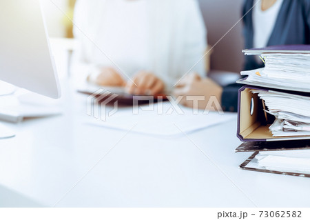 Accountant checking financial statement or counting by calculator income for tax form, hands closeup. Business woman sitting and working with colleague at the desk in office. Tax and Audit concept Accountant checking financial statement or counting by calculator income for tax form, hands closeup. Business woman sitting and working with colleague at the desk in office. Tax and Audit concept 73062582