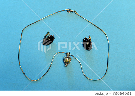 Pendant with a pearl on a chain and two earrings with a dark stone on the table. Pendant with a pearl on a chain and two earrings with a dark stone on the table. 73064031