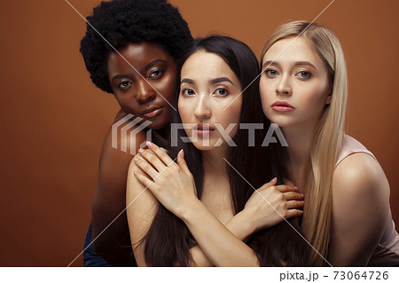 young pretty asian, caucasian, afro woman posing cheerful together on brown background, lifestyle diverse nationality people concept 73064726