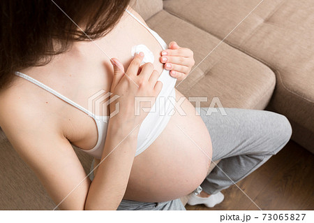 pregnant woman applying stretch mark cream to belly. pregnancy, people and maternity concept. pregnant apply anti-stretch mark cream on her breast pregnant woman applying stretch mark cream to belly. pregnancy, people and maternity concept. pregnant apply anti-stretch mark cream on her breast 73065827