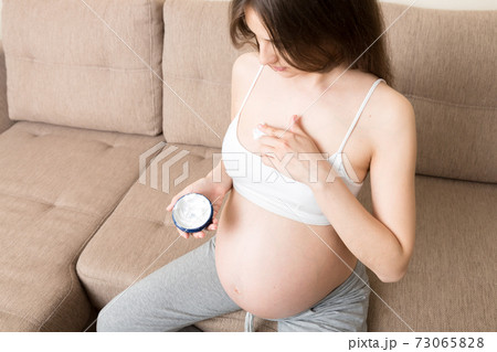 pregnant woman applying stretch mark cream to belly. pregnancy, people and maternity concept. pregnant apply anti-stretch mark cream on her breast pregnant woman applying stretch mark cream to belly. pregnancy, people and maternity concept. pregnant apply anti-stretch mark cream on her breast 73065828