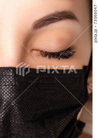 Eyelash Extension Procedure. Beautiful Woman with Extreme Long False Eyelashes. Makeup, Cosmetics. Beauty, Skincare. Woman in medical mask. Eyelash Extension Procedure. Beautiful Woman with Extreme Long False Eyelashes. Makeup, Cosmetics. Beauty, Skincare. Woman in medical mask. 73066047