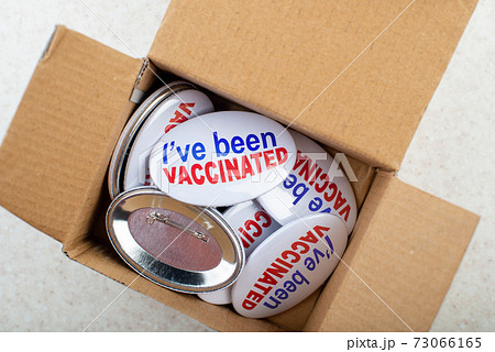 Vaccination campaign button pins in carton box on light tabletop flat lay view 73066165