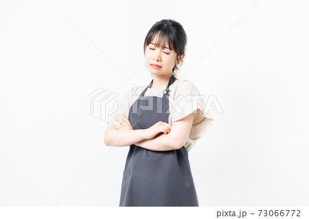 腕を組んで悩むエプロンを着た女性 73066772