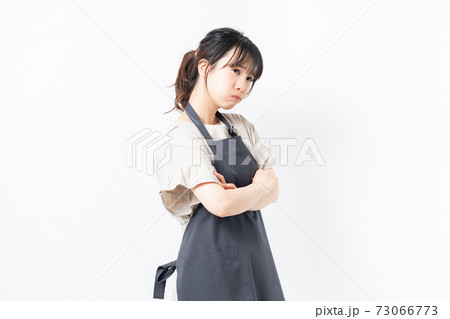 腕を組んで悩むエプロンを着た女性 73066773