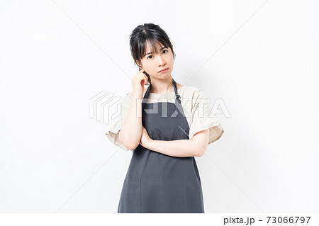 考え事をするエプロンを着た若い女性 73066797