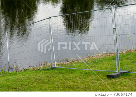 a metal wire fence that delimits the area to the water a metal wire fence that delimits the area to the water 73067174