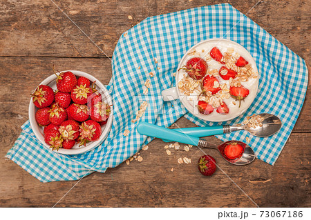 In a cup of yogurt, oat granola and fresh strawberries, on a blu 73067186