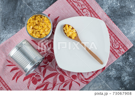 A wooden spoon of popcorn seeds on an empty plate 73067908