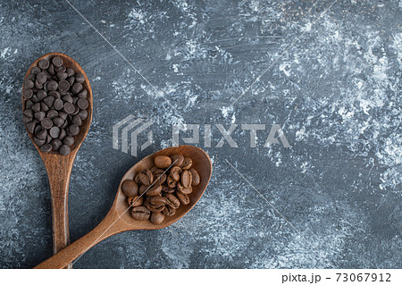 Wooden spoons of chocolate chips and coffee beans Wooden spoons of chocolate chips and coffee beans 73067912
