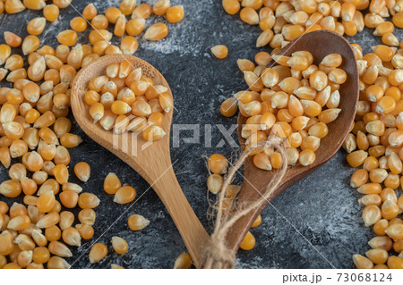 Wooden spoons of sweet corns on marble background 73068124