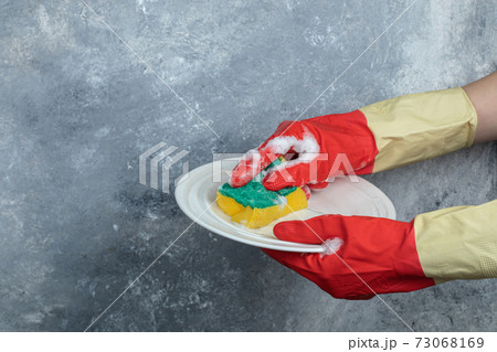 Hands in protective gloves washing plate with sponge Hands in protective gloves washing plate with sponge 73068169